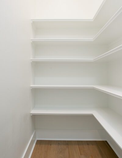Empty white shelves in a clean, modern pantry.